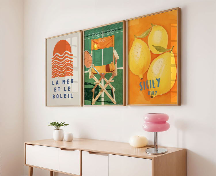 Three colorful framed artworks on a wall above a wooden console table.