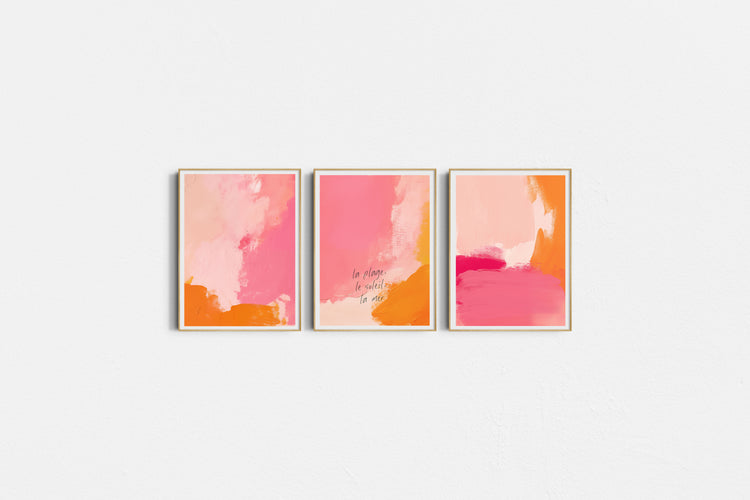 Three abstract art prints in pink and orange on a white wall