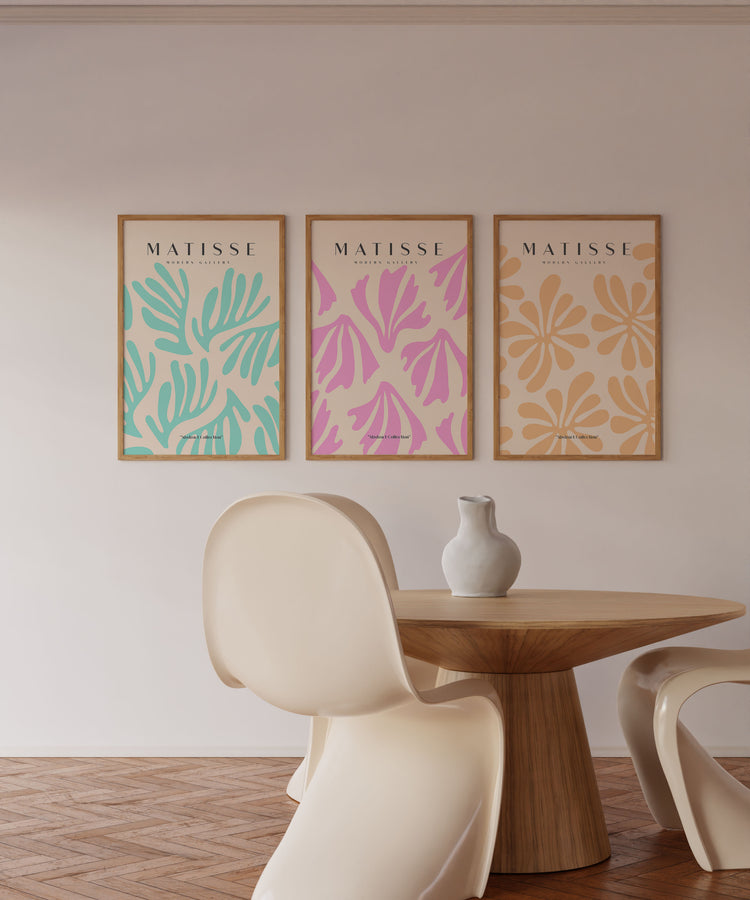 Three Matisse art prints on a wall above a wooden table and chairs.