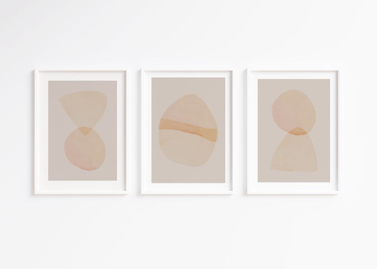 Three abstract art prints with geometric shapes in soft colors on a white wall.