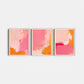Three abstract art prints in pink and orange on a white wall