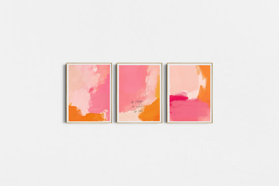 Three abstract art prints in pink and orange on a white wall