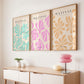 Three framed artworks with floral patterns above a wooden console table.