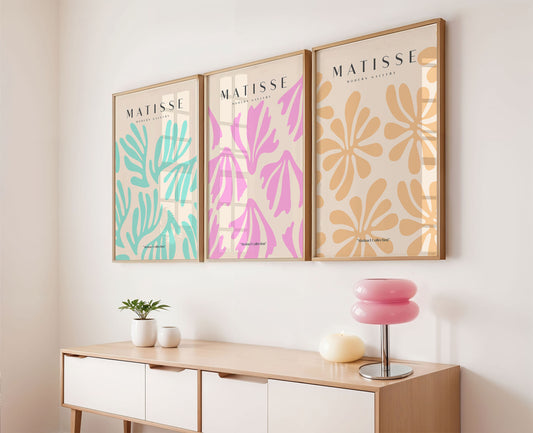 Three framed artworks with floral patterns above a wooden console table.