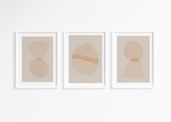 Three abstract art prints with geometric shapes in soft colors on a white wall.